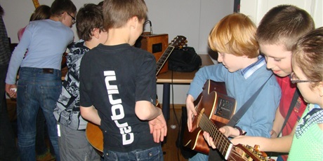Powiększ grafikę: dzieci próbują grać na gitarze