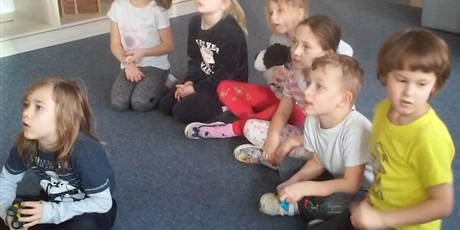 Powiększ grafikę: dzieci siedzą na dywanie i słuchają nauczyciela