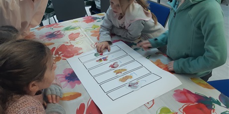 Powiększ grafikę: Dziewczynki układają obrazki przedstawiające żywność.