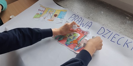 Powiększ grafikę: Dzieci przyklejają obrazki o swoich prawach na wspólny plakat.