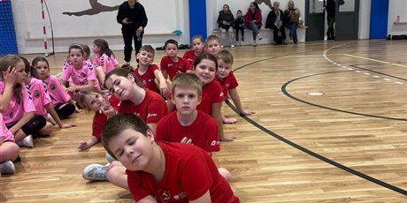 Powiększ grafikę: drużyny dzieci siedzą na parkiecie