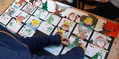 Powiększ grafikę: Dzieci wkładają do kieszonek papierowe aniołki, choinki, mikołaje i renifery.