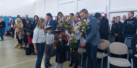 Powiększ grafikę: Uczniowie wręczają kwiaty dyrekcji szkoły.