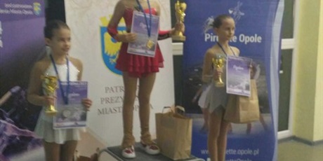 Powiększ grafikę: dzieczynki z  medalami i dyplomomami stoją na podium