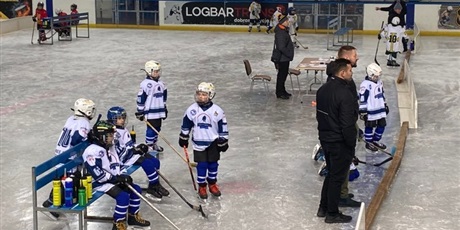 Powiększ grafikę: Trenerzy oraz grupka hokeistów podczas meczu mini hokeja na lodzie
