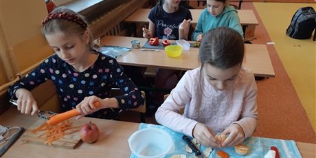 Powiększ grafikę: Dzieci obierają marchewkę i mandarynkę.